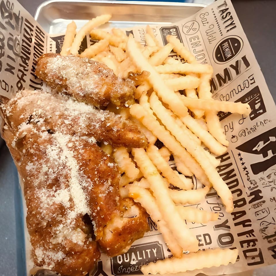 Crispy chicken wings dusted with parmesan cheese and a side of golden french fries.